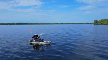 Kano balıkçılarının ve balıkçıların destansı hava manzarası gölün tadını çıkarırken kanoda balık tutuyor ve yazın gölün ortasında fotoğraf çekiyor. Balıkçı kanosu. Mavi gökyüzü ve bulutlar arka plan.
