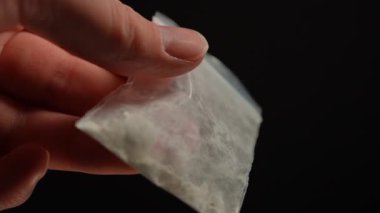 Uyuşturucu satıcısının eli, kulüplerde, partilerde ve sokaktaki bağımlılara satılmak üzere küçük plastik torbalarda reçeteli opioid haplarıyla gösteriş yapıyor. Yasadışı uyuşturucu ticareti, bağımlılık ve aşırı doza neden olur