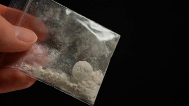 Uyuşturucu satıcısının eli, kulüplerde, partilerde ve sokaktaki bağımlılara satılmak üzere küçük plastik torbalarda reçeteli opioid haplarıyla gösteriş yapıyor. Yasadışı uyuşturucu ticareti, bağımlılık ve aşırı doza neden olur 