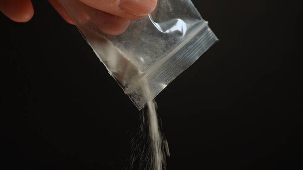 Человек, готовящий нелегальные уличные наркотики, такие как белый кристаллический порошок для употребления фыркая. Опиоидная эпидемия является серьезным кризисом общественного здравоохранения, приводящим к наркомании, передозировке и смерти.