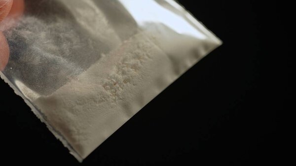 Crushed oxycodone or Heroin maid of opioid medications placed in small plastic container. Become powdered illegal drug stored for sale at clubs, party and streets, indicating substance abuse. 
