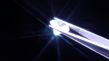 Cımbızdaki elmas seçici odaklanma, inceleme ve parlak kesim kristal cilası kalitesini analiz etme. Stüdyoda profesyonel kuyumcu el yapımı. Makro çekim, yüzeysel derinlik.