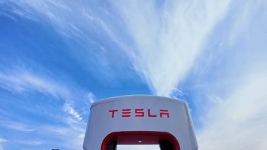 Tesla, Kanadalı bir lastik dükkanının dışındaki geniş bir otoparkta şarj ediyor. Kentsel bir ortamda modern elektrikli araç altyapısı: Toronto, Ontario, Kanada - 20 Eylül 2024