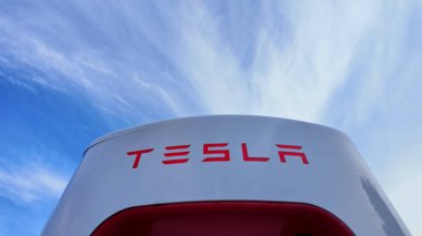 Tesla, Kanadalı bir lastik dükkanının dışındaki geniş bir otoparkta şarj ediyor. Kentsel bir ortamda modern elektrikli araç altyapısı: Toronto, Ontario, Kanada - 20 Eylül 2024