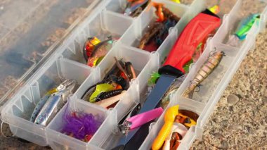 Ahşap kaya yüzeyinde yapay balıkçı teçhizatı bulunan olta çantası. Balık seçici odaklanma için aksesuarları yakından çek. Crankbait üç kat yem ya da kaşık, jig spinner, yumuşak plastik ve yüzme yemi