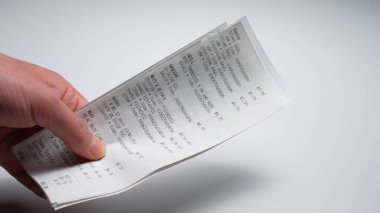 Alışveriş sonrası elinde bir sürü çek ve kağıt makbuzu tutan bir adam. Alışveriş bağımlılığı ve kontrol edilemeyen alışveriş anlayışı. Ev ailesi ve kişisel finans, para harcamaları ve tüketim bağımlılığı. 