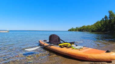 Spor aletleri, açık hava aktiviteleri, sarı su geçirmez çanta, sakin göl suyunda kürek çekme. Su sporu ve hobi aletleri. Kanada 'da seyahat ve macera. 
