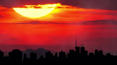 Şehrin ufuk çizgisi silueti, sıcak sinematik güneş batımı, şehir merkezi, büyük güneş batımı ışığı olan şehir merkezi. Sanatsal efektler. Binalar ve sarı güneş diskleriyle destansı sıcak yaz gökyüzü. Isı dalgası uyarısı.
