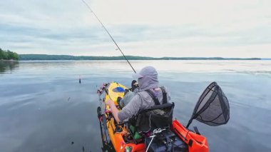 Sabahın erken saatlerinde sakin sularda kanoyla balık tutan bir adam. Balıkçılık yaparken balıkçıyı vitesli ve sarı kanoyla görmek. Rüzgarsız sakin bir sabah suyu. Balıkçılık oyunu ve su hobisi.