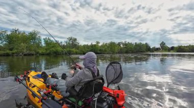 Balıkçılık sporu sırasında gölde ya da gölette kano küreği. Balıkçı, pedallı kano kürekleri ve oyuncu kadrosuyla. Boş zaman aktif yaşam tarzı eğlencesi ve spor aktivitesi.
