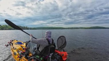 Balıkçılık sporu sırasında gölde ya da gölette kano küreği. Balıkçı, pedallı kano kürekleri ve oyuncu kadrosuyla. Boş zaman aktif yaşam tarzı eğlencesi ve spor aktivitesi.