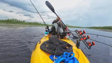 Göl kenarında kano küreği ya da sert rüzgâr fırtınasında bataklık. Balıkçı, güçlü fırtına rüzgârıyla savaşmak için pedallı kano kürekleriyle geliyor. Boş zaman aktif yaşam tarzı eğlencesi ve spor aktivitesi.