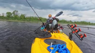 Göl kenarında kano küreği ya da sert rüzgâr fırtınasında bataklık. Balıkçı, güçlü fırtına rüzgârıyla savaşmak için pedallı kano kürekleriyle geliyor. Boş zaman aktif yaşam tarzı eğlencesi ve spor aktivitesi.