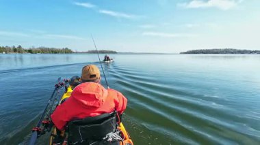 Balıkçılar ya da balıkçılar göl suyunda balık avı turnuvasındayken motorlu pedallarla kano balıkçılığı yapıyorlar. Kano balıkçılığı ve su sporu. Baharda su sporu.