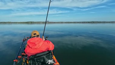 Kano balıkçısı gölde balık tutmak için kano, olta ve küçük yem kullanıyor. Balıkçı, Kuzey Amerika sularında kano yapıyor, balık tutuyor ve balık tutuyor. Baharda su sporu. Balıkçılık oyunu.