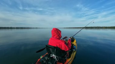 Kano balıkçısı gölde balık tutmak için kano, olta ve küçük yem kullanıyor. Balıkçı, Kuzey Amerika sularında kano yapıyor, balık tutuyor ve balık tutuyor. Baharda su sporu. Balıkçılık oyunu.