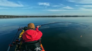 Kano balıkçısı gölde balık tutmak için kano, olta ve küçük yem kullanıyor. Balıkçı, Kuzey Amerika sularında kano yapıyor, balık tutuyor ve balık tutuyor. Baharda su sporu. Balıkçılık oyunu.