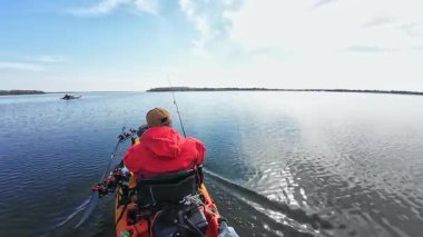 Balıkçılar ya da balıkçılar göl suyunda balık avı turnuvasındayken motorlu pedallarla kano balıkçılığı yapıyorlar. Kano balıkçılığı ve su sporu. Baharda su sporu.