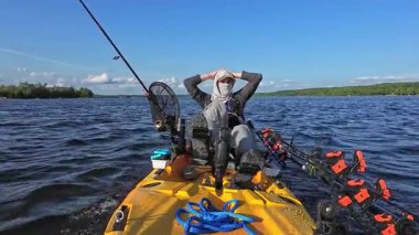Balıkçı balıkçı balıkçılığı ve güneş kremi kapüşonlu kapüşonlu levrek yarışmasından sonra yalnızlık içinde dinleniyor. Balıkçı, sıcak öğleden sonra kayıkla açılışa motorlu kano sürüyor. Balık avı turnuvası..