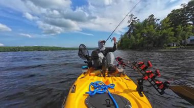 Güneş kremi kapüşonlu balıkçı ve şapka balıkçı kanosuyla olta ipi hazırlayın. Güneşli bulutlu bir günde gölün ortasında tek başına vakit geçirmek. Balıkçılar balıkçılar turna balığı için dönen çubuklar kurar..
