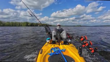 Adam güneşli bir günde gölde kanoyla geziyor. Spor balıkçılık oyunu. Erkek turist kano ya da küçük tekne, su sporları. Turuncu motorlu kayıkta balıkçılık yarışması sırasında dinlenen balıkçı..