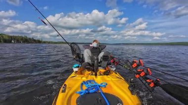 Adam güneşli bir günde gölde kanoyla geziyor. Spor balıkçılık oyunu. Erkek turist kano ya da küçük tekne, su sporları. Turuncu motorlu kayıkta balıkçılık yarışması sırasında dinlenen balıkçı..