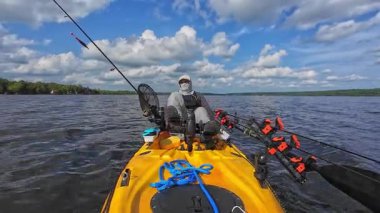 Balıkçı balıkçı balıkçılığı ve güneş kremi kapüşonlu kapüşonlu levrek yarışmasından sonra yalnızlık içinde dinleniyor. Balıkçı, sıcak öğleden sonra kayıkla açılışa motorlu kano sürüyor. Balık avı turnuvası..