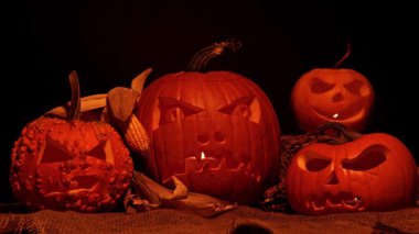 Cadılar Bayramı balkabakları ön bahçe dekorasyonu için karanlık bir düzenleme. Azizler Günü ruhları cehennem ve mistik arka plan, oyulmuş kafalarda yanan mumlar..