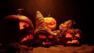 Cadılar Bayramı balkabakları ön bahçe dekorasyonu için karanlık bir düzenleme. Azizler Günü ruhları cehennem ve mistik arka plan, oyulmuş kafalarda yanan mumlar..