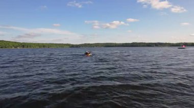 Altın saat batımında gölün ortasında yüzen balıkçıyla sarı kanonun kayık görüntüsü. Aktif insanlar spor seyahati konsepti. Kano ve dalgaların manzarası.