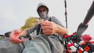 Kano balıkçılarının boş vakitleri ve hobileri. İnsan balık avını pov view 'e yakın bir yerde sergiliyor. Dönen çubuk ve olta ile eğlence. Gölde balık tutmak ve serbest bırakmak levrek, panfish.