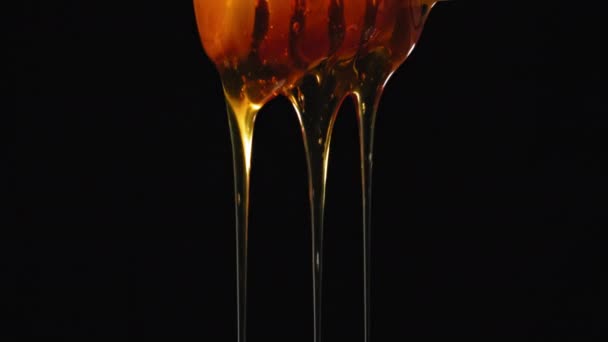 Close Orange Honey Teče Dolů Dřevěnou Lžíci Černém Izolovaném Pozadí — Stock video
