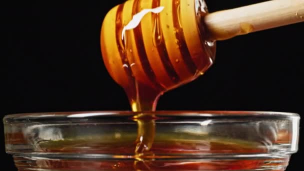 木製の蜂蜜スティック上を流れる蜂蜜をガラスカップ プラスチックリサイクルに閉じます 高品質4K映像 — ストック動画