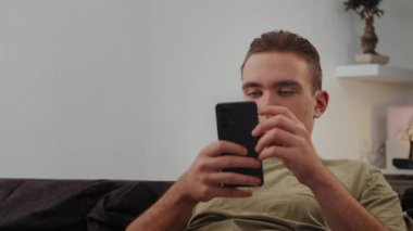 Genç adam telefona bakar ve internette sıkıcı bir alışveriş için sörf yapar. Yüksek kalite 4k görüntü