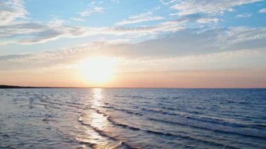 Güneş denizin üzerinde batarken, dingin dalgalar altın renginde parlıyor, dinlenme, rahatlama ve hak edilmiş bir tatil kavramını somutlaştıran rahatlatıcı bir ortam yaratıyor..