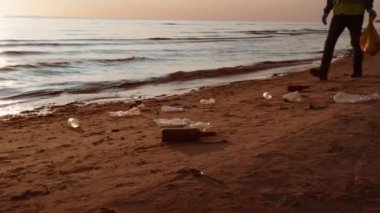 Gönüllü, okyanus kıyısında plastik çöpleri topluyor. Çevre Koruma ve Sorumluluk Konsepti