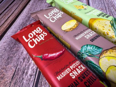 Jurmala, Letonya - 22 Eylül 2024 Üç farklı Uzun Cips paketi ahşap bir yüzeyde, acı biber gibi tatların yer aldığı