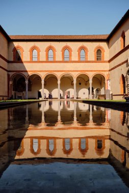 Milano, İtalya, 03.07.2024: Sforza Kalesi içeride. Gölette büyük bir mimarinin yansıması..