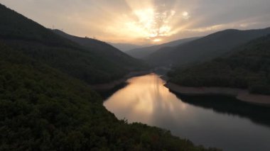4K hava görüntüsü. İHA 'nın günbatımı videosu, güneş ışınları bulut kümülüsünün arkasındaki su yüzeyine yansıyor..