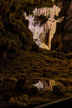 Doku ve yansımanın çarpıcı etkileşimi Oylat Mağarası 'nın derinliklerinde, damlayan oluşumlar ve su birikintisinin yansıması mağaraların katmanlı mineral dramı..