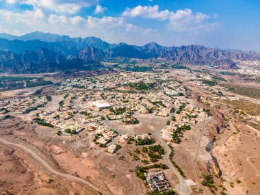 Hatta town aerial cityscape surrounded by Hajar mountains in Hatta enclave of Dubai in the United Arab Emirates aerial view clipart