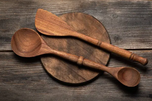 Wooden round board or pizza plate on a wooden table and two wooden spoons for mixing food.Rustic kitchen set