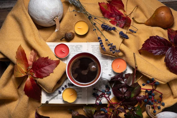 Autumn theme with autumn fruits and colors. A yellow sweater with a cup of coffee on it, a book, autumn leaves, small scented candles and various fruits. Hello autumn