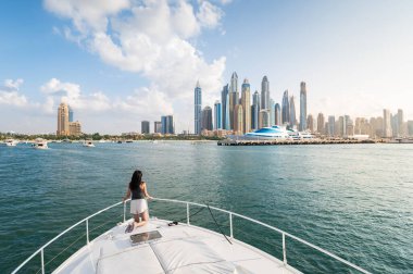 Enchanting beauty of Dubai Marina as a stylish woman embraces the tranquil sunset during a luxurious yacht ride. Capturing the essence of sophistication and relaxation against the iconic Dubai cityscape in the United Arab Emirates clipart