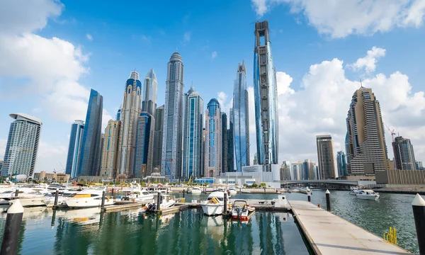 在阿拉伯联合酋长国的一个阳光明媚的日子里 迪拜的港湾与繁华的大都市交汇在一起 船只在宏伟的城市天际线下航行 高耸的摩天大楼映衬着它们 映照在下面宁静的湖中 图库图片