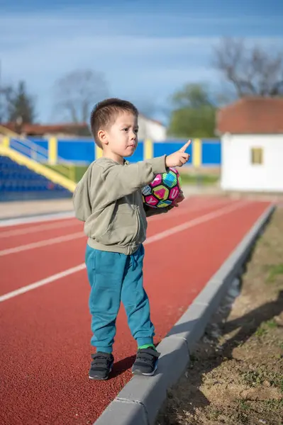 Радісний Хлопчик Малюк Стискає Яскравий Футбольний Трасі Сигналізуючи Про Футбольний Ліцензійні Стокові Зображення