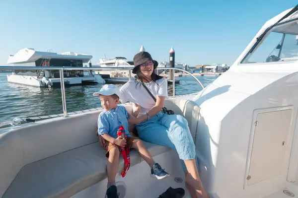 stock image A young boy enjoys a boat ride with his mother at Al Bandar Marina near Yas Island, with the Abu Dhabi skyline in the background They could be an Asian family exploring the UAE waters