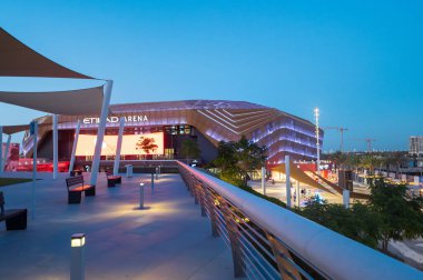 Abu Dhabi, United Arab Emirates - May 3, 2024: Bustling entrance of the Etihad Arena on Yas Island, with people gathered in Abu Dhabi, UAE, under a twilight sky clipart