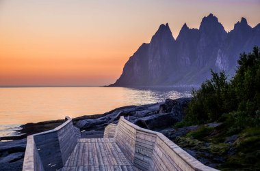 Senja, Norveç ve Avrupa 'daki keskin dağların ardında güzel bir günbatımı.