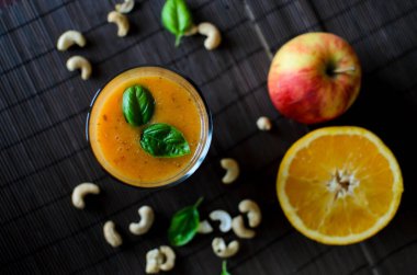 Koyu arkaplanda elma, havuç ve fındıklı taze çiğ portakal suyu.